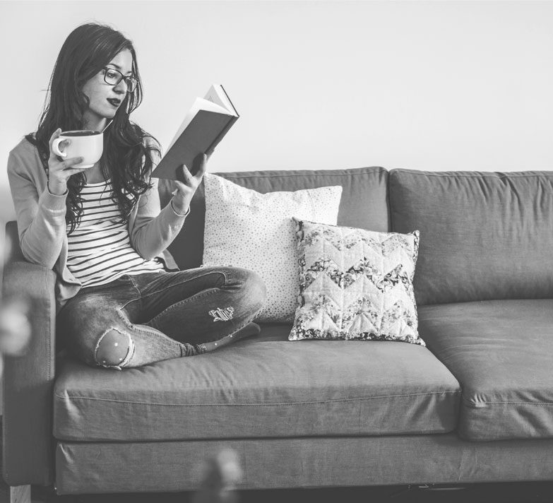 A woman sitting on a sofa reading a book